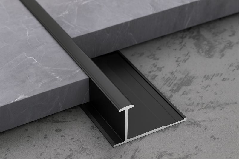 Black metal threshold strip between two gray tiled surfaces